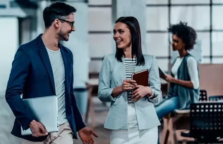 Dos profesionales conversando alegremente en una oficina moderna.